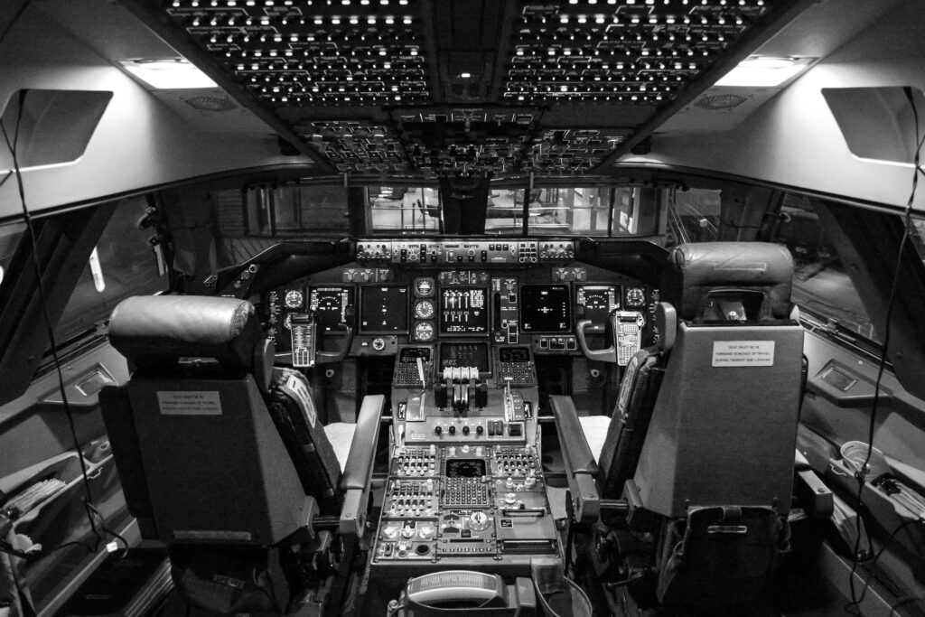 Black and white image of airplane cockpit showing instruments and controls.