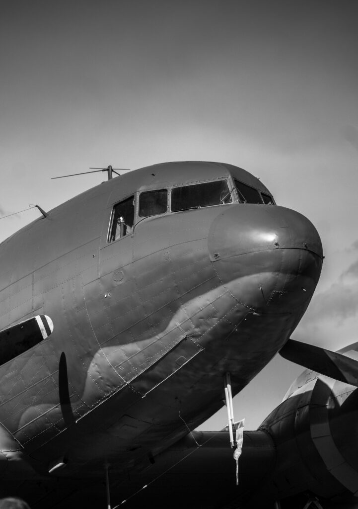 A low-angle monochrome photo of a vintage aircraft showcasing its sleek design and classic appeal.